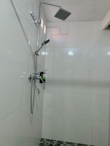 a shower in a bathroom with white tiles at Lokasea Villa Bali in Pengastulan