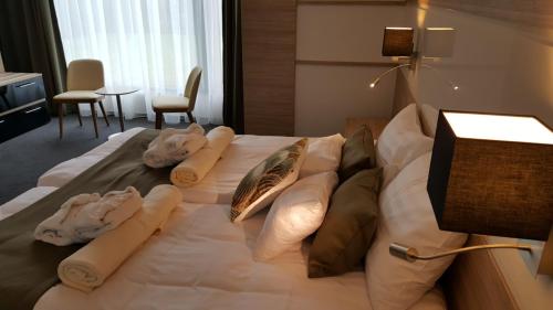 a bed in a hotel room with towels on it at Hotel Zena Beauty & Shopping Center in Hévíz