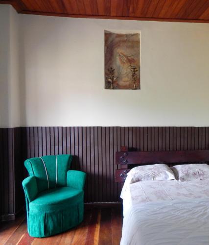 a bedroom with a green chair next to a bed at Casa de Mariazinha in Ouro Preto