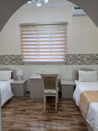a bedroom with two beds and a chair and a window at Al-Adl Guest House in Bukhara