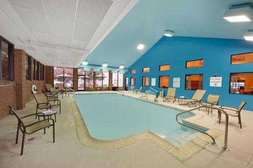 a pool in a room with chairs and a pool at Holiday Inn Express Fredericksburg - Southpoint by IHG in Fredericksburg