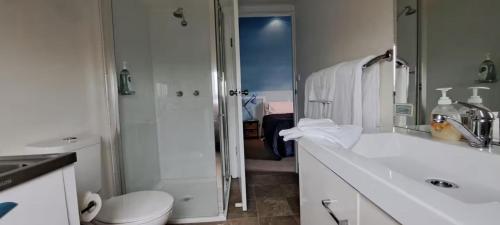 a white bathroom with a toilet and a shower at Blue Monkey Mountains in Newnes Junction