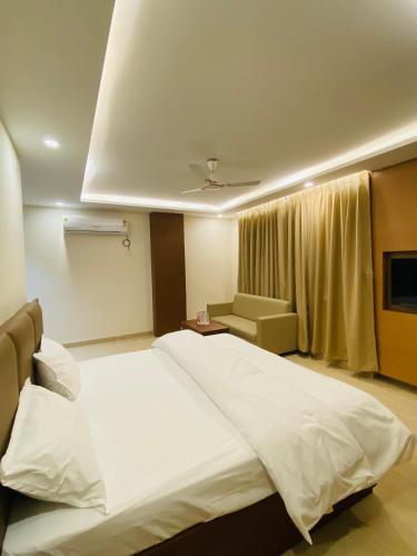 a bedroom with a large white bed and a couch at Hotel Ananta in Sasarām