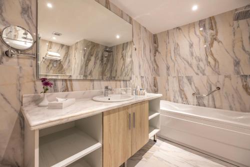 a bathroom with a sink and a tub at Helnan Antoniades Palace Hotel in Alexandria
