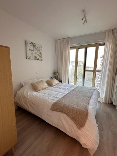 a bedroom with a large bed and a large window at Spacious and modern apartment with open sea view in Ostend