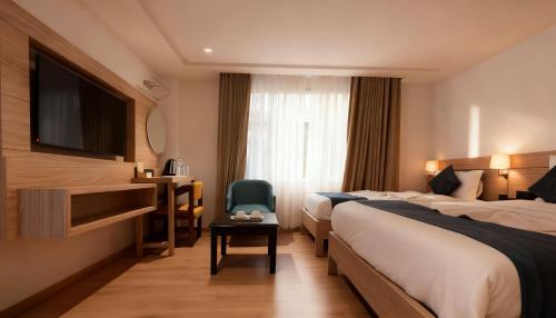 a hotel room with two beds and a television at Hotel Tenki Kathmandu in Kathmandu