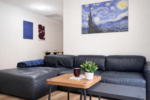 a living room with a black leather couch and a table at Epping Station Apartments in Epping