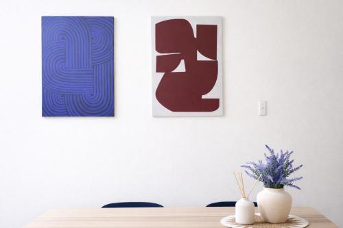 a table with three paintings on a white wall at Epping Station Apartments in Epping