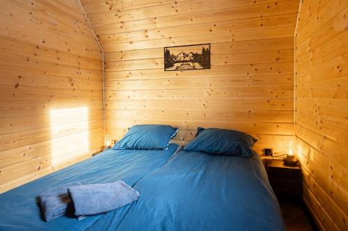a bedroom with a blue bed in a wooden room at Barn&Haus-Stodoły Widokowe in Zubrzyca Dolna