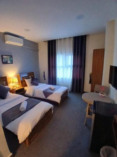 a hotel room with two beds and a desk at Kahraman Amman Hotel in Amman