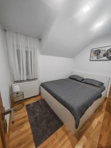 a white bedroom with a bed and a window at Apartman Antonela in Sop