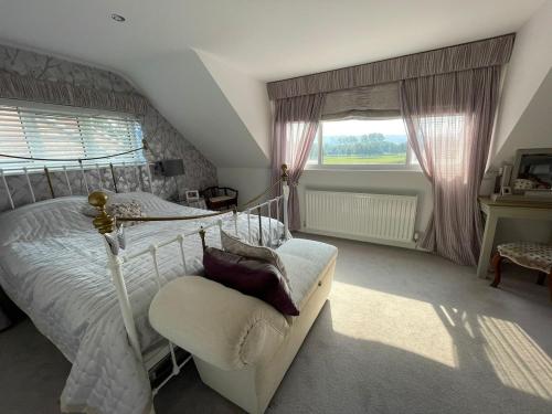 a bedroom with a bed and a chair and a window at The Cherries in Penrhyn Bay