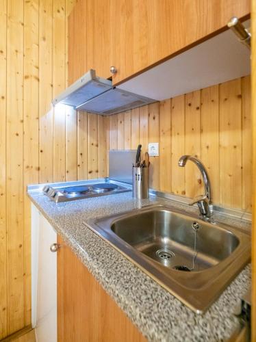a kitchen with a stainless steel sink and wooden walls at La Borda del Pubill Resort in Ribera de Cardós