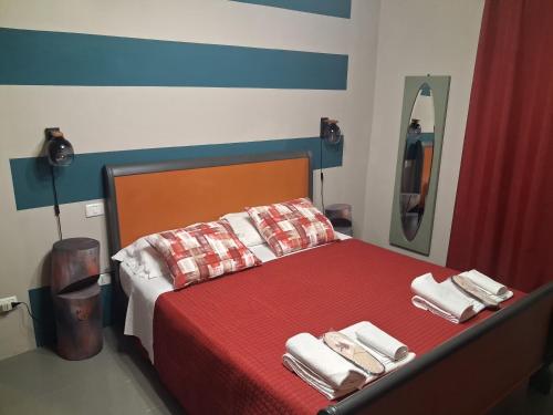 ein Schlafzimmer mit einem roten Bett, Handtüchern und einem Spiegel in der Unterkunft Bb Casolara2 in San Giovanni