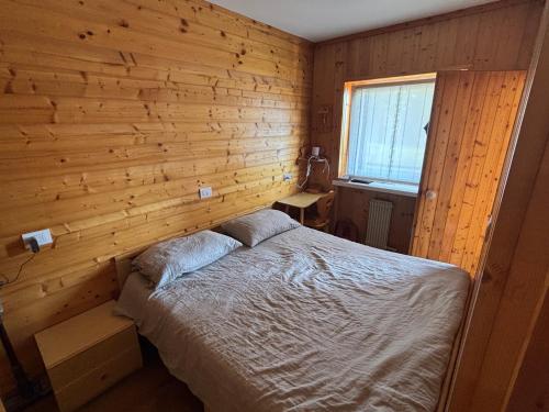 a bedroom with a bed in a wooden wall at Il Nido - Family Apartment con Spa & Mini Club a Cavalese in Carano
