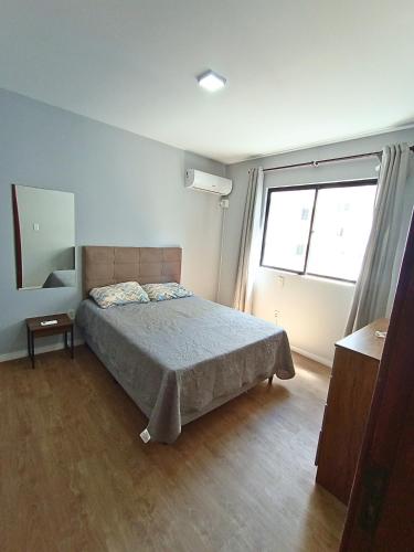 a bedroom with a bed and a large window at Duplex 11 Pessoas-Churrasqueira-Próximo ao Mar in Itapema