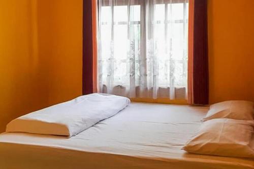 an unmade bed in a room with a window at Bromo Indah Lestari Homestay Mitra RedDoorz in Pasuruan