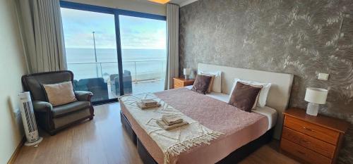 a bedroom with a bed and a chair and a window at Ocean Breeze Apartment in São Vicente