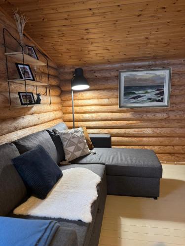 a living room with a couch and wooden walls at Viihtyisä hirsimökki Venturissa in Siurlahti