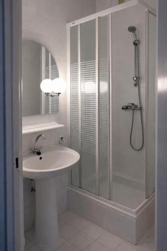 a white bathroom with a sink and a shower at Pensjonat Kowalski in Łubowo