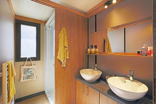 a bathroom with two sinks on a counter with a window at Camping Les Lavandes in Darbres