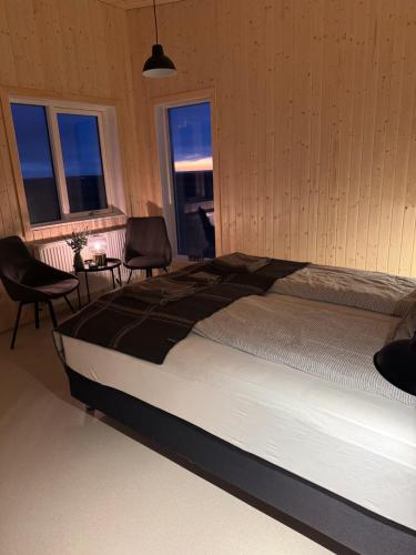a bedroom with a bed and two chairs and windows at New listing - Krosshóll Cottage, built in 2026 in Hella
