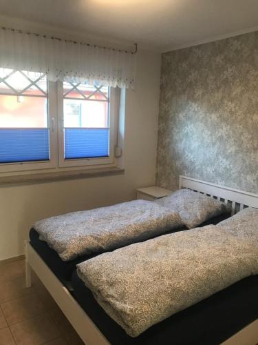 two beds in a bedroom with two windows at Sommerwiese in Prerow