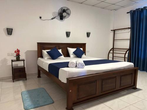 a bedroom with a bed with blue and white pillows at Looma House Hiriketiya in Dickwella