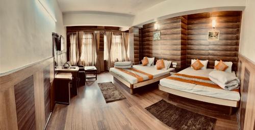 a hotel room with two beds and a desk at Hotel Marvel International And Restaurant in Darjeeling