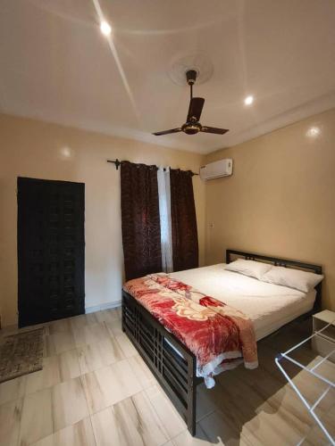 a bedroom with a bed and a ceiling fan at Stepping Stone Apartments in Bijilo