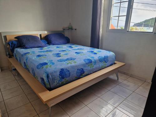 a bedroom with a bed with a blue comforter and a window at La maison du Pêcheur in Terre-de-Haut