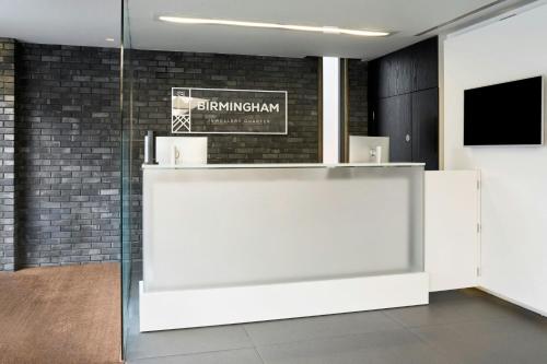 a lobby with a reception desk and a television at Four Points Flex by Sheraton Birmingham Jewellery Quarter in Birmingham
