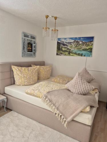 a bedroom with a bed with pillows and a painting at Ferienwohnung Tiroler Auszeit & Whirlpool in Hofen