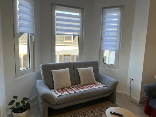 a couch sitting in a living room with windows at Ferienwohnung Andi in Gerolstein