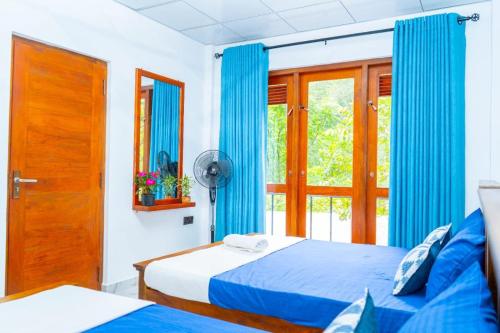 a bedroom with two beds and a window with blue curtains at Ella Flower Zone Holiday Resort in Bandarawela