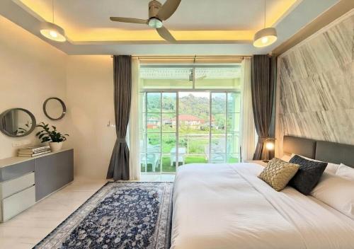 a bedroom with a large bed and a large window at Kamala Beach Phuket - 4BR Private Luxury Pool Villa with Maid in Kamala Beach
