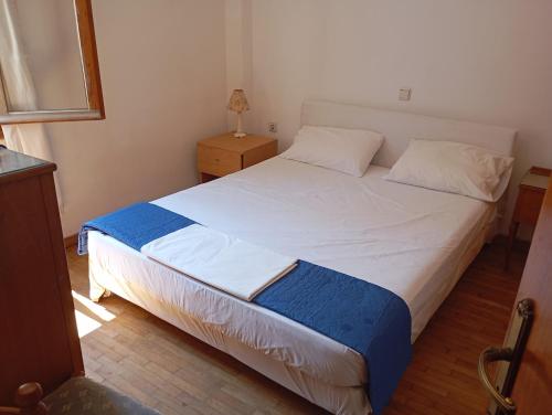a bedroom with a large white bed with blue and white sheets at Dafnis beach house in Karavostamo
