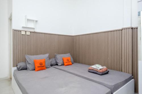 a bed with two orange pillows in a room at Omah Ninten Syariah Laweyan RedPartner in Solo