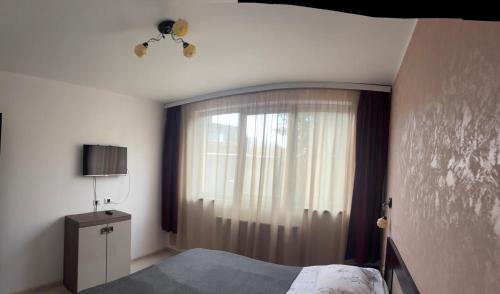 a bedroom with a bed and a large window at KM 0 one RESIDENCE in Piatra Neamţ