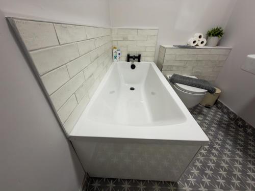 a white bath tub in a bathroom with a toilet at Luxury 2-Bedroom Apartment Overlooking the Beach in Bundoran