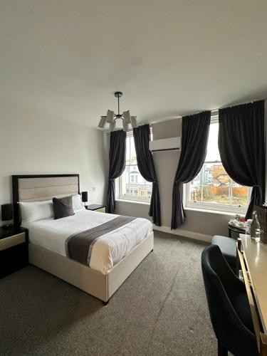 a bedroom with a bed and two windows at The Royal Hotel - Clacton On Sea in Clacton-on-Sea