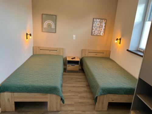 two beds in a room with green sheets at Barrierefreie Ferienwohnung Morgentau in Pewsum, 1 - 4 Personen in Krummhörn