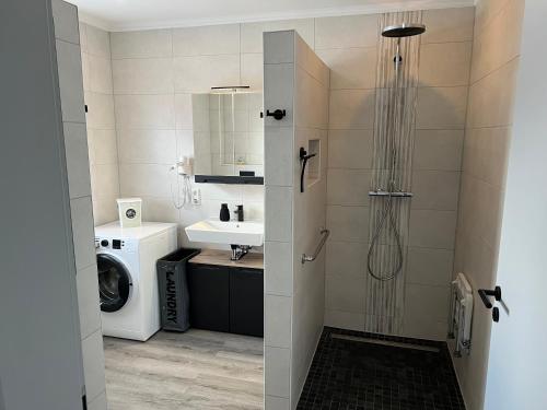 a bathroom with a shower and a sink and a washing machine at Barrierefreie Ferienwohnung Morgentau in Pewsum, 1 - 4 Personen in Krummhörn
