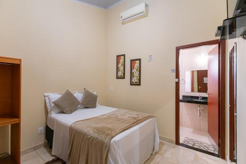 a bedroom with a white bed and a mirror at Pousada Pouso Vitoria in Pirenópolis