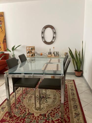 un tavolo da pranzo in vetro con sedie e uno specchio di AkyaSpot a Praia