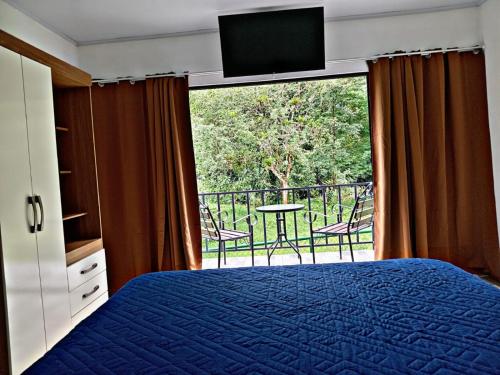 a bedroom with a bed and a balcony with a television at The Chicken House in El Castillo de La Fortuna