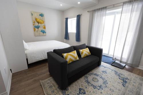 a living room with a black couch and a bed at Cozy Cove Retreat, Private Suite with Separate Entrance Near Friday Harbour, Barrie & Lake Simcoe in Innisfil