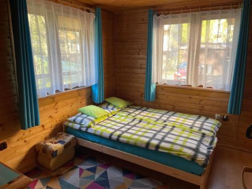 a small bed in a room with two windows at PanTuszka Pokoje in Pobierowo