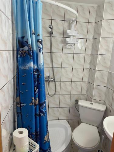 a bathroom with a toilet and a blue shower curtain at PanTuszka Pokoje in Pobierowo