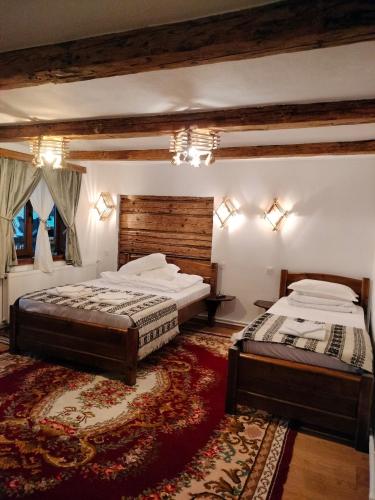 a bedroom with two beds and a rug at Wild-Traditional Bucovina in Câmpulung Moldovenesc